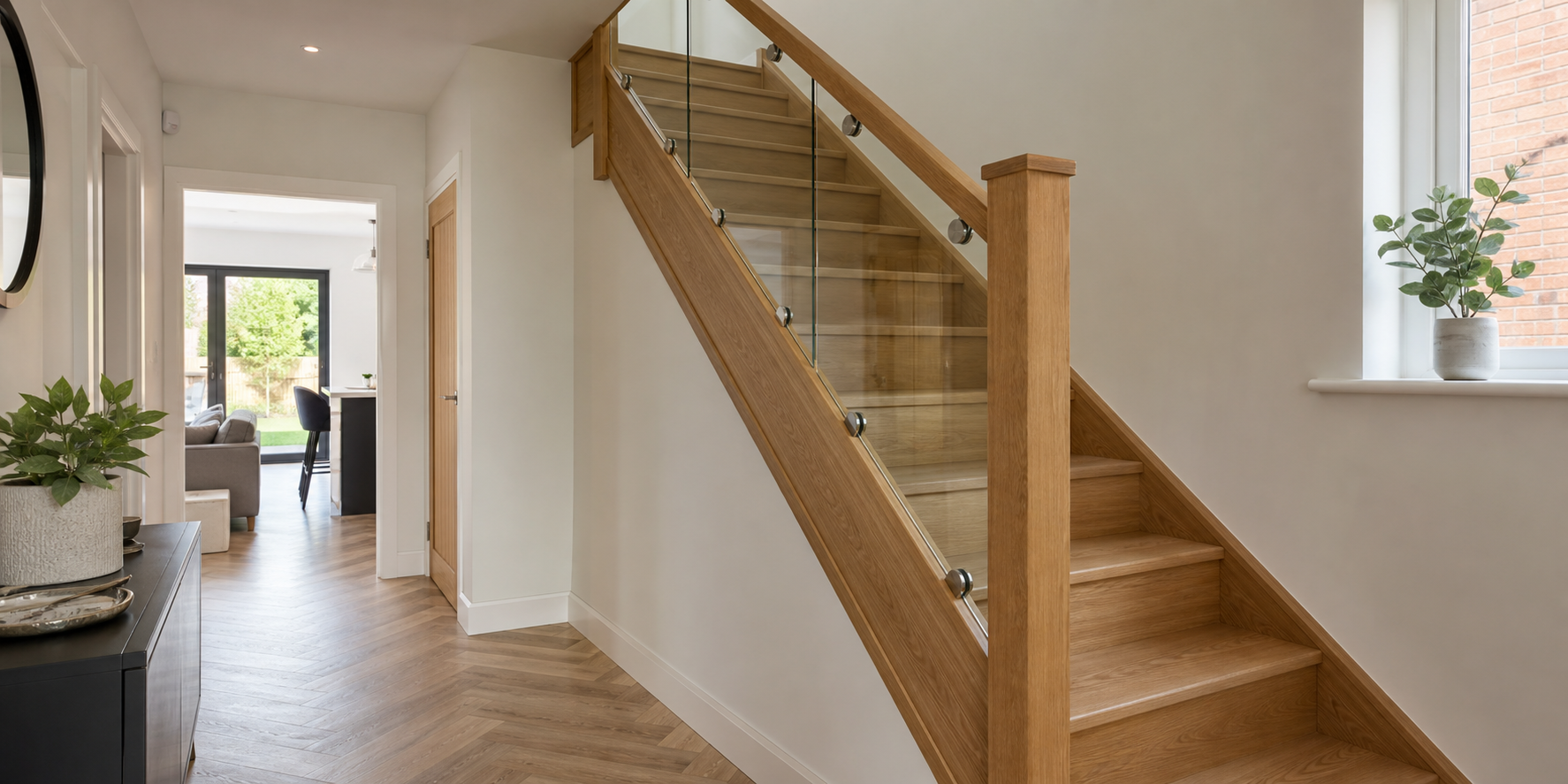 Modern oak and glass staircase refurbishment with glass balustrades and oak handrail in a bright hallway